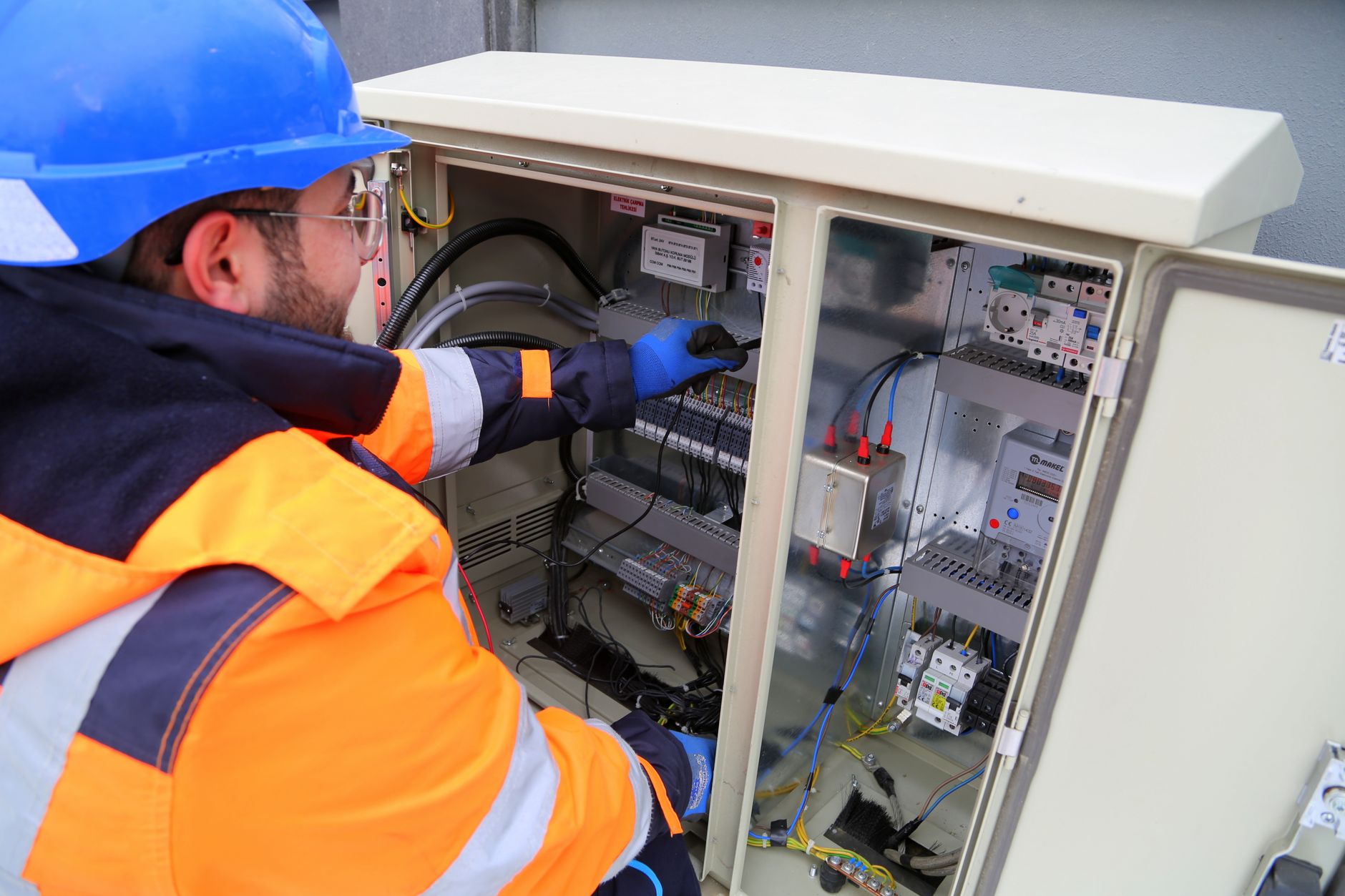 Eletricista trabalhando em quadro de distribuição elétrica